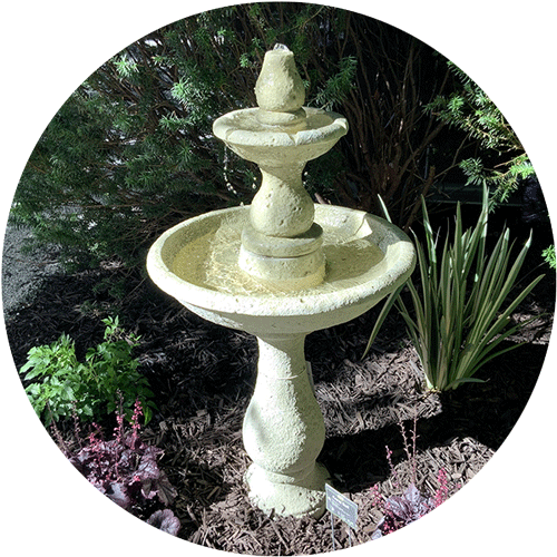 A red glazed ceramic fountain in a yard.